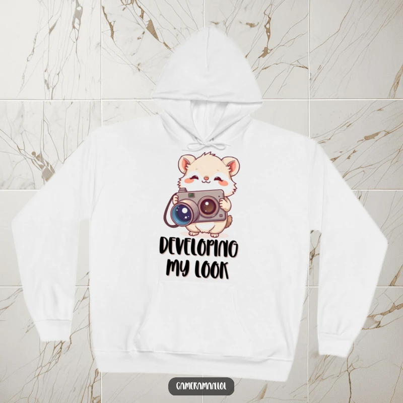 Funny hoodie depicting a small, fluffy animal curiously holding a large, vintage camera, perfect for cozy, humorous moments.