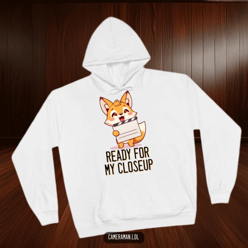 Funny, excited fox sprite with a movie clapperboard, depicted on a cozy hoodie for film enthusiasts.